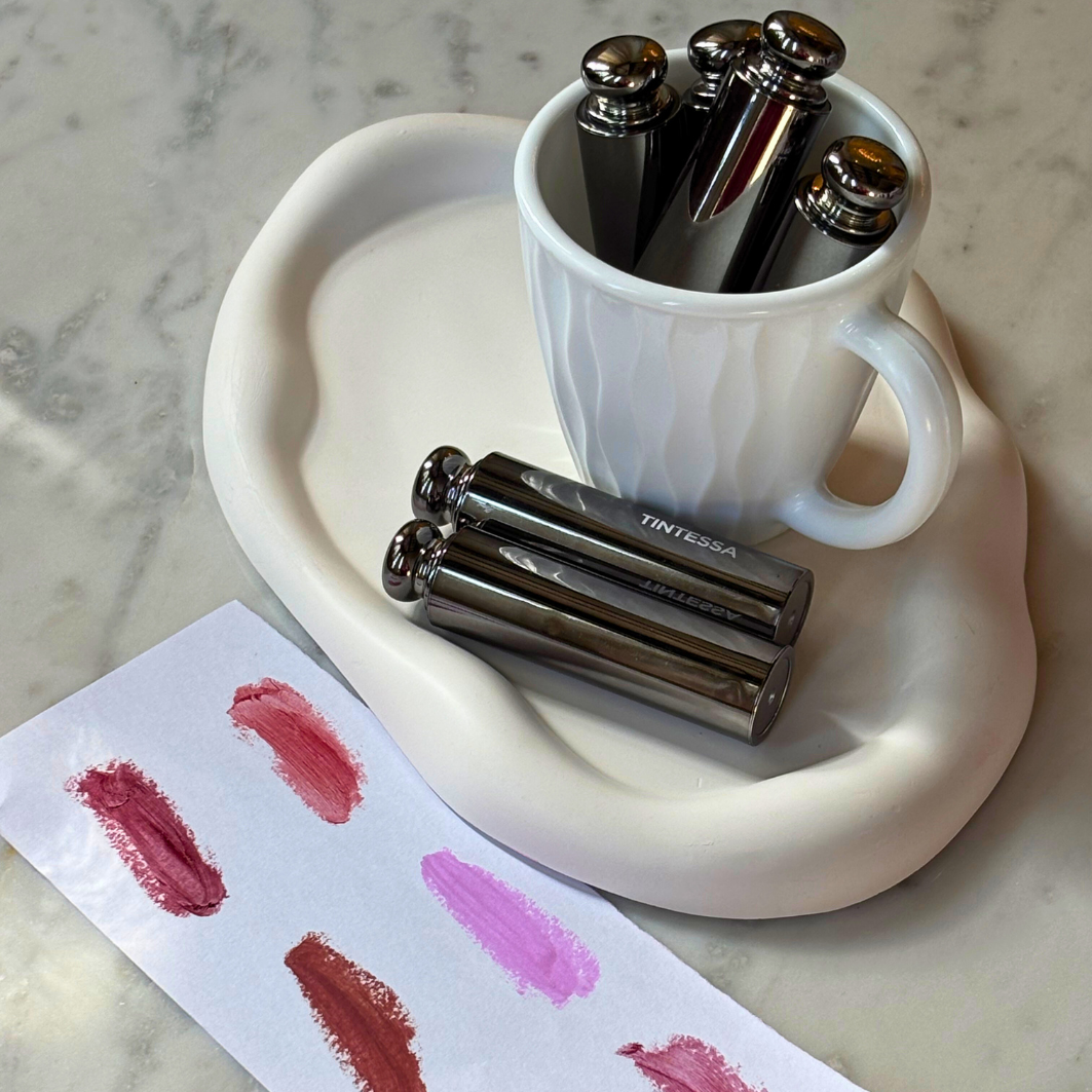 Tintessa's skincare supercharged lip butter kept neatly on a pretty surface along with paper swatches