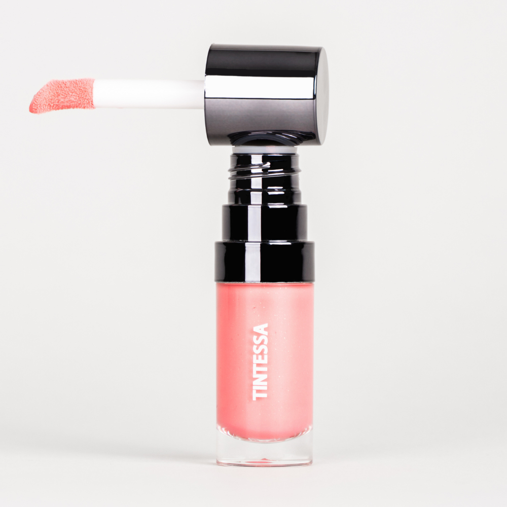 Cheek, lips and lids multi-use tint in pink colour with applicator on a white background